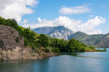 Scenic ferry boat tour on Lake Koman reservoir on Drin river surrounded by forested steep hills, cliffs and majestic rugged mountain ranges of Albanian Alps. Panoramic view along Albanian Fjords. Awe