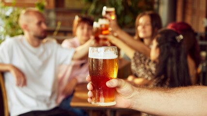 Game brings thrill, and fans bring cheers, raising their glasses in celebration and excitement. Friday mood. Selective focus. Concept of Oktoberfest, brewery, vacation, Friday mood.