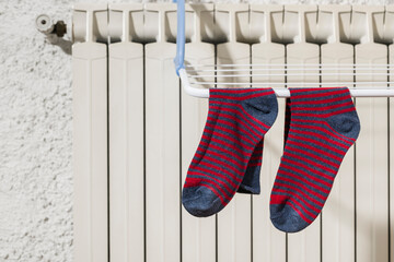 Colorful socks hanging on the clothesline drying on the radiator at home in winter.