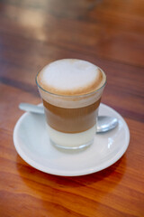 Leche y leche, a traditional Spanish coffee-based drink, a hot beverage consisting of layers of creamy condensed milk, an espresso shot topped with a frothy layer of steamed milk served in a glass cup