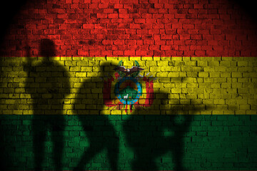 Fototapeta premium bolivia flag on brick wall and soldiers shadow