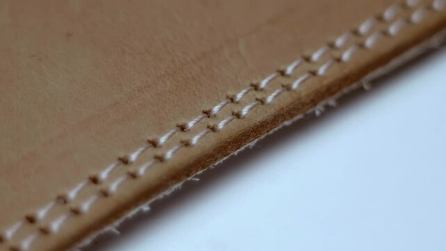 The edge of the brown leather product is stitched with double stitching. Closeup. Macro. Shallow depth of field. Shot in motion