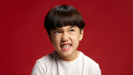 Child displays fierce, energetic expression, teeth showing in moment of pure intensity against bold...