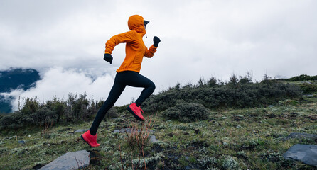 Woman trail runner cross country running to high altitude mountain peak © lzf