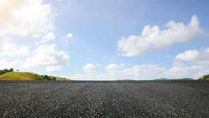 Asphalt street and mountain range view with blue sky and clouds in the background. The sky is clear and the clouds are fluffy