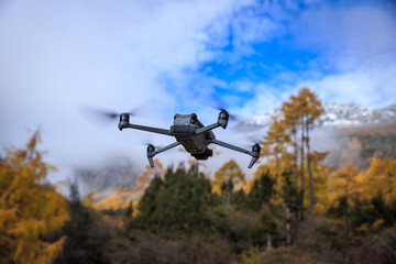 Fototapeta premium Flying drone taking photo of autumn forest landscape and snow capped mountains