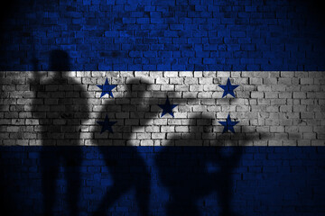 honduras flag on brick wall and soldiers shadow