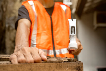 Workers in safety vest using hammer to to work assembling pallet parts