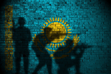 kazakhstan flag on brick wall and soldiers shadow