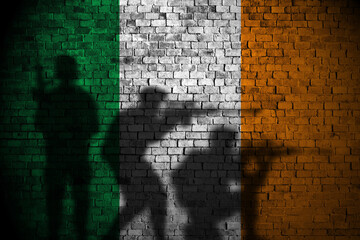 ireland flag on brick wall and soldiers shadow