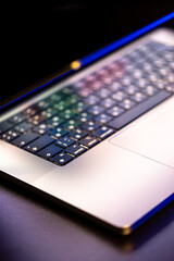 A laptop computer with a half-open screen on a dark background.