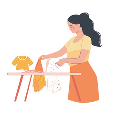 A pregnant woman folding baby clothes at a table