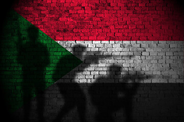 sudan flag on brick wall and soldiers shadow