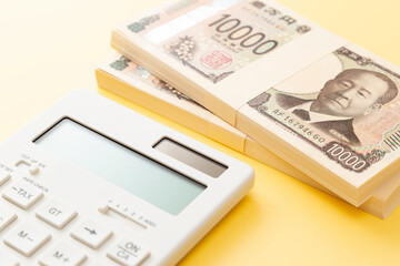 黄色背景に一万円の札束と電卓