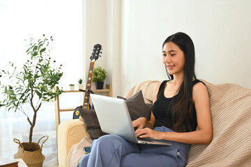 Fototapeta premium Attractive young female freelancer working on a laptop in a living space at home