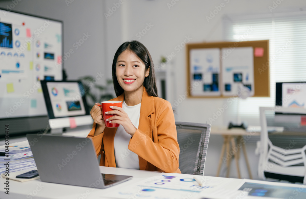 Poster young manager is taking a break, holding a mug and smiling in her bright modern office. she is surro
