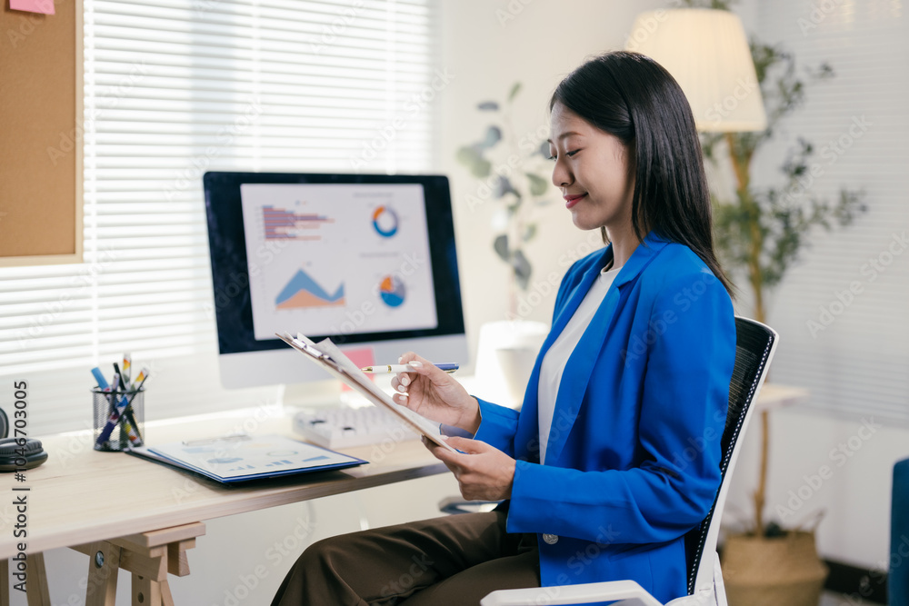 Wall mural confident young asian businesswoman in a modern office, analyzing financial data on her computer, ta