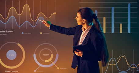 Sleek businesswoman explains advanced data concepts with glowing graphical representations. Concept of presentation, training, meeting, leadership, analysis. Copy space for ad.