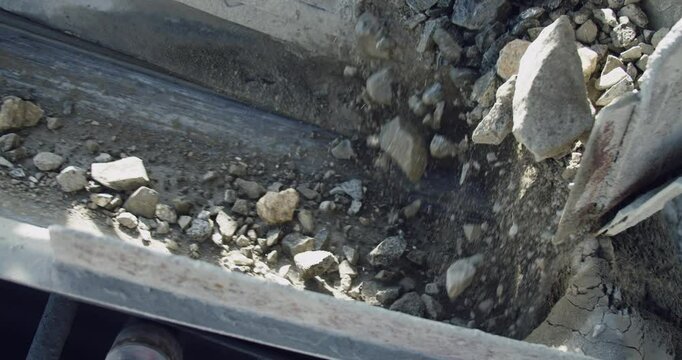 Stone crusher machine, rocks drop on conveyor belt in slow motion, close up