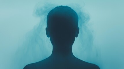 Fototapeta premium A silhouette of a person against a misty blue background, evoking a sense of mystery and introspection.