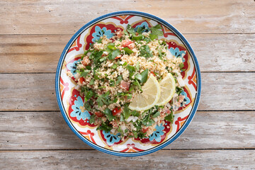 Tabbouleh salad with couscous on wooden table. Top view