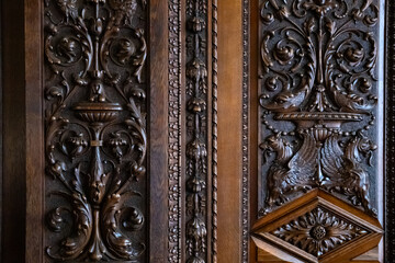 Elaborate woodwork on an antique door highlights detailed carvings of floral and animal motifs, revealing expert craftsmanship from earlier centuries, rich in history.