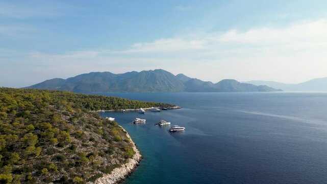 Yachts parked in harbor on Greek island with other island silhouette in distance