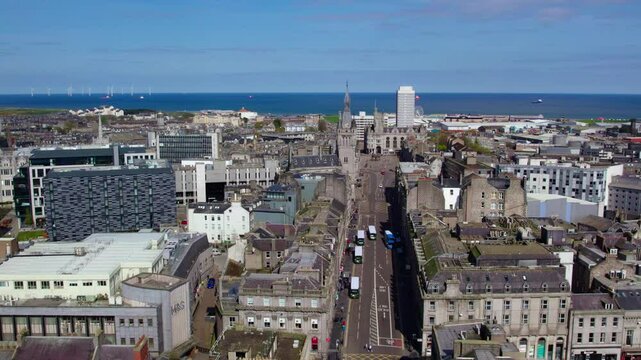 A drone captures Aberdeen&rsquo;s city streets stretching toward the North Sea, with a clear view of offshore wind turbines and historic architecture. The vibrant coastal cityscape is highlighted from above