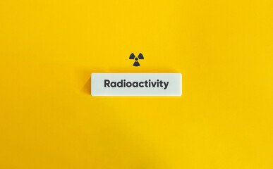 Radioactivity Sign and Text on Block Letter Tile on Yellow Background. Minimal Aesthetic.