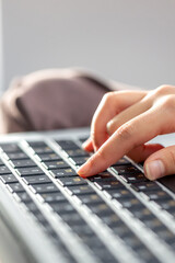 The girl is typing on the laptop keyboard. Girl's hands on the keyboard.