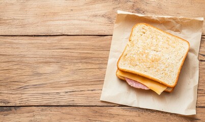 delicious ham and cheese sandwitch on a piece of paper on a wooden table