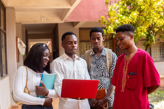 A diverse group of students engages in a collaborative project using a laptop outside university buildings, fostering teamwork, learning, and creativity in an academic environment.