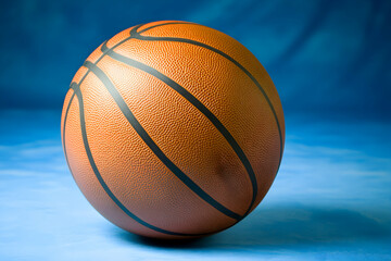 Obraz premium Basketball on Blue: A close-up shot of a classic orange basketball against a vibrant blue background, evoking the thrill of the game and the anticipation of a slam dunk. 