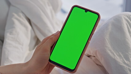 Hand holding mockup smartphone in bed calm morning closeup. Unknown woman phone