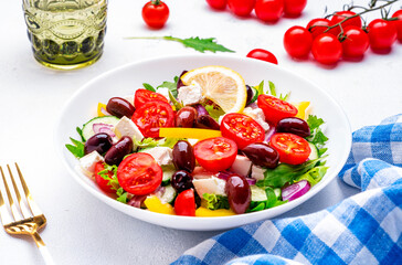 Mediterranean salad with vegetables, olives, cheese and lettuce, white background, top view