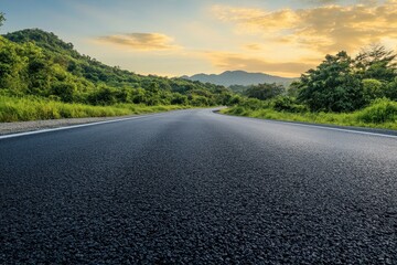 A winding asphalt road leading through a scenic landscape with green hills, lush vegetation, and a...
