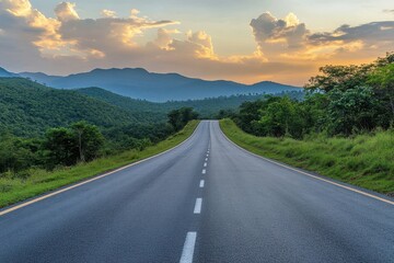 A scenic road winding through a mountain valley at sunset.