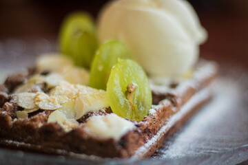 Chocolate wafer with almond flakes, scoop of vanilla ice cream and sliced ​​grapes