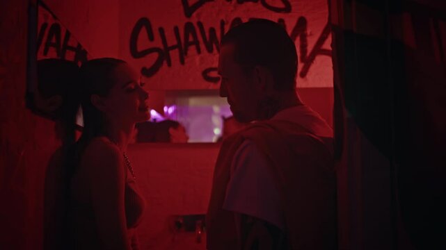 Young couple flirting party at graffiti wall nightclub light backdrop closeup. 