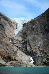 A distant view at the Briksdalsbreen glacier and its turquoise colored glacial lake in Briksdal,...