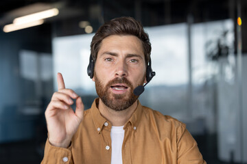 Obraz premium Business professional on video call using headset communicates key points while gesturing to emphasize ideas. Office setting enhances focus on remote work and modern communication technology.