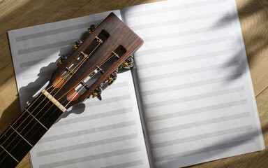 Close-up of sheet music notebook and acoustic guitar neck. Music inspiration concept. Copy space