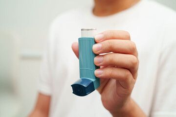Asthma and chronic obstructive pulmonary disease COPD, Asian young man using metered dose inhaler...