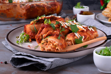 Enchiladas with crepes, chicken meat, tomato sauce and cheese served with sour cream and herbs. Fusion cuisine meal