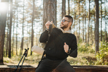 Young caucasian man drinking water taking break from hiking or trekking