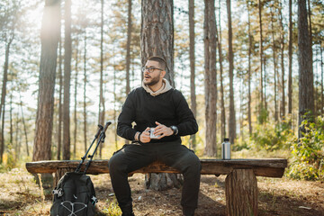 Young caucasian man drinking water taking break from hiking or trekking