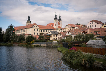 Fototapeta premium View of Jesuit College and Historic Telč with Pond on a Partly Cloudy Autumn Morning