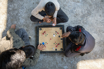 Indian village boys focus intently on a carrom board while playing together in a courtyard, surrounded by pastel-colored walls and a calming atmosphere.
