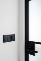 Modern black light switches next to a sleek glass door in room