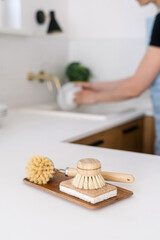 A person washing dishes in a modern kitchen while eco-friendly cleaning tools